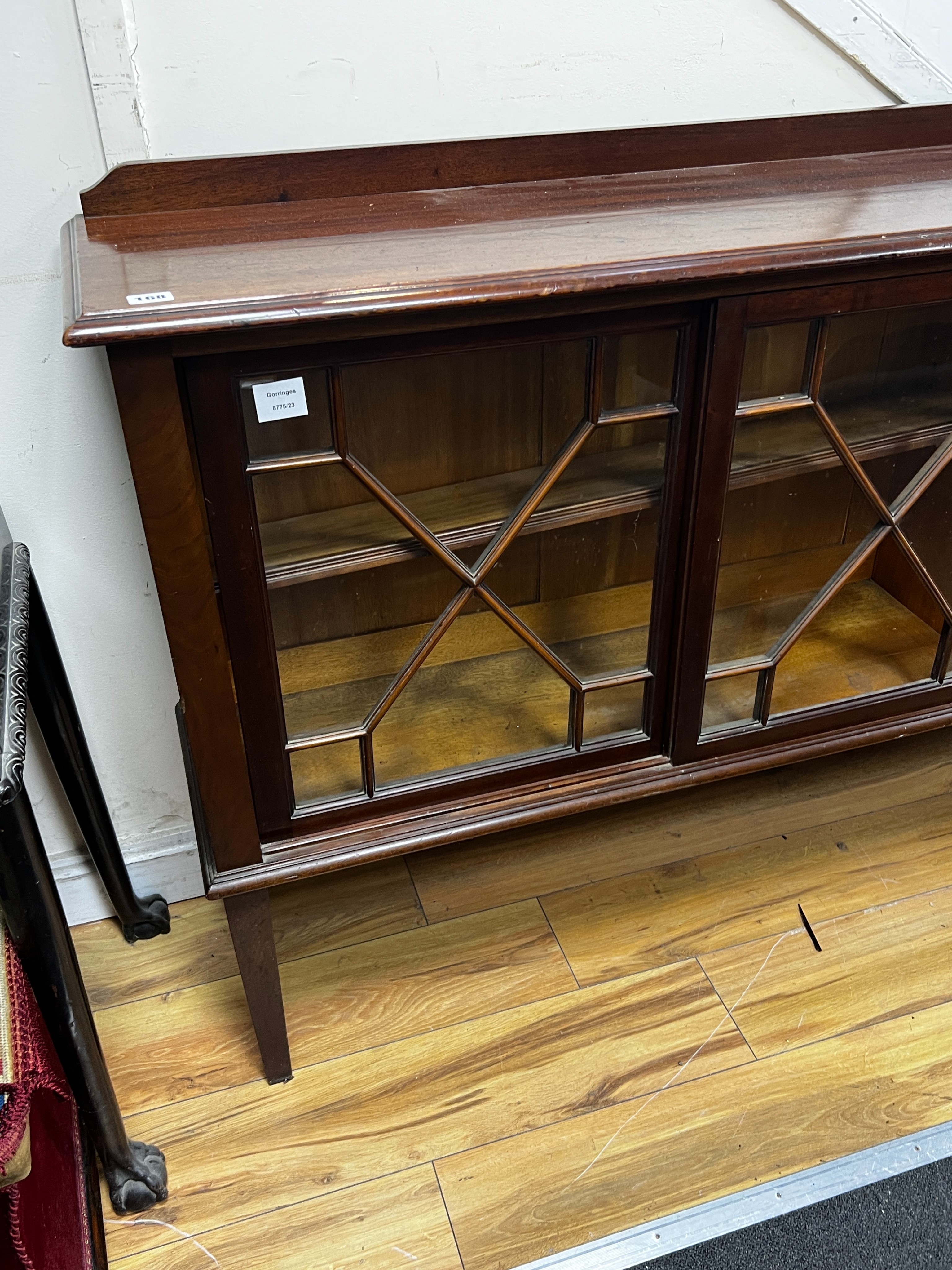 An Edwardian glazed mahogany dwarf bookcase, enclosed by six astragal glazed sliding doors, width 290cm, depth 34cm, height 94cm